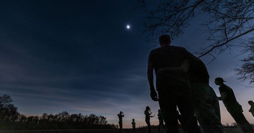 Performance Testing - A group of people standing in the dark with the moon in the sky